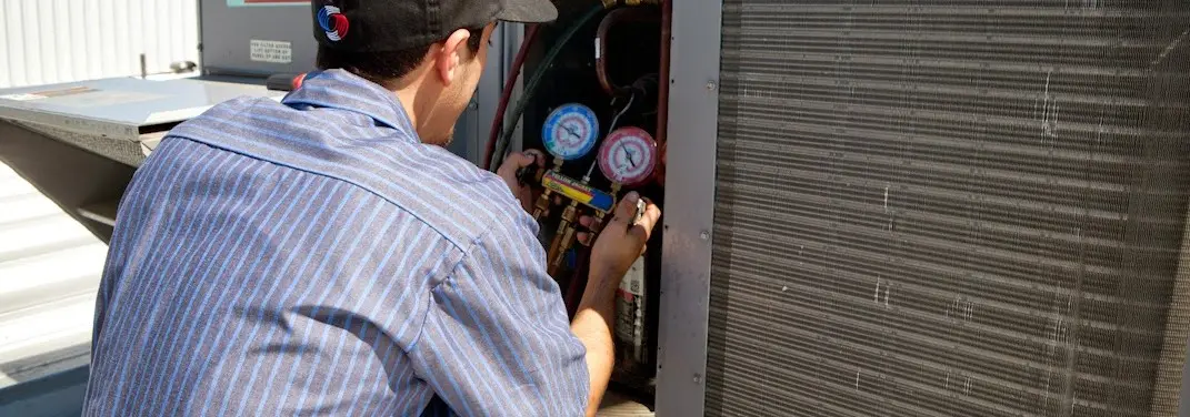 HVAC technician servicing a condenser unit in Saugus